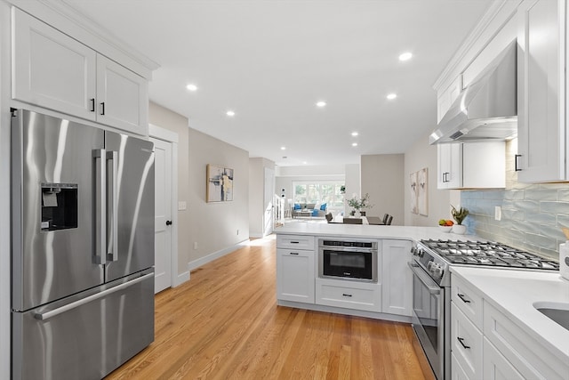 kitchen with stainless steel appliances, light hardwood / wood-style floors, white cabinets, kitchen peninsula, and wall chimney exhaust hood