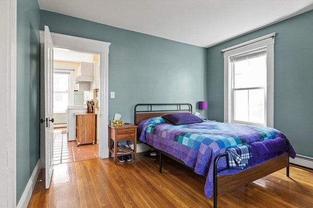 bedroom featuring baseboards, baseboard heating, and wood finished floors