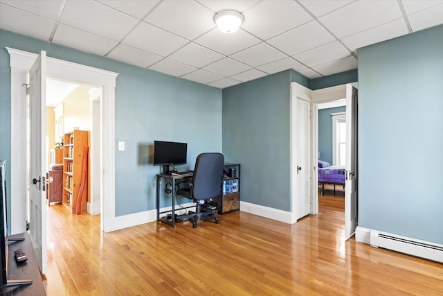 home office with a drop ceiling, baseboard heating, and wood finished floors