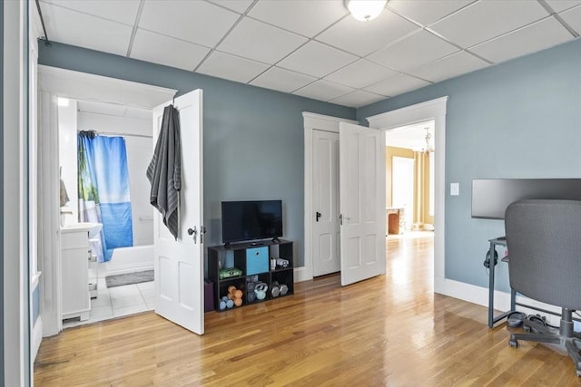 office space featuring baseboards, a drop ceiling, light wood-type flooring, and a chandelier