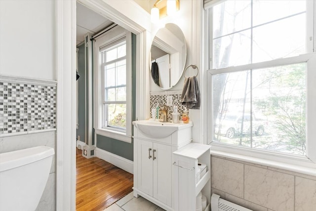bathroom featuring toilet, tile walls, and a healthy amount of sunlight