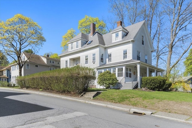 view of front of home with a chimney, a porch, and a front lawn