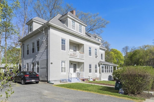 view of front of home featuring a chimney and a balcony