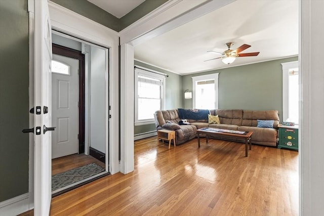 living area with a ceiling fan, a baseboard heating unit, and wood finished floors