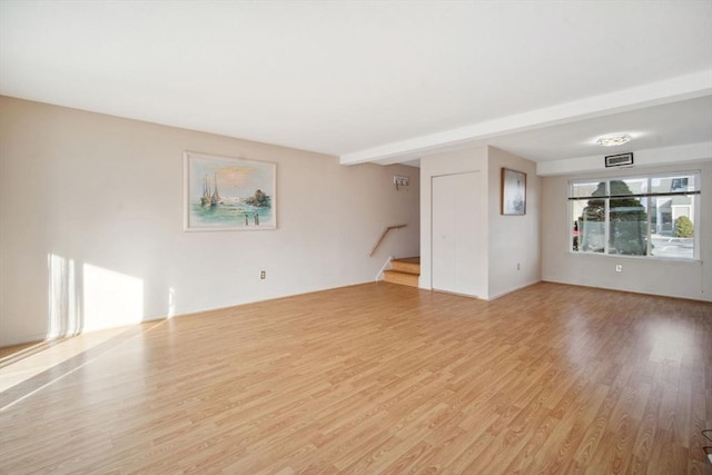 unfurnished living room featuring beam ceiling and light wood-type flooring