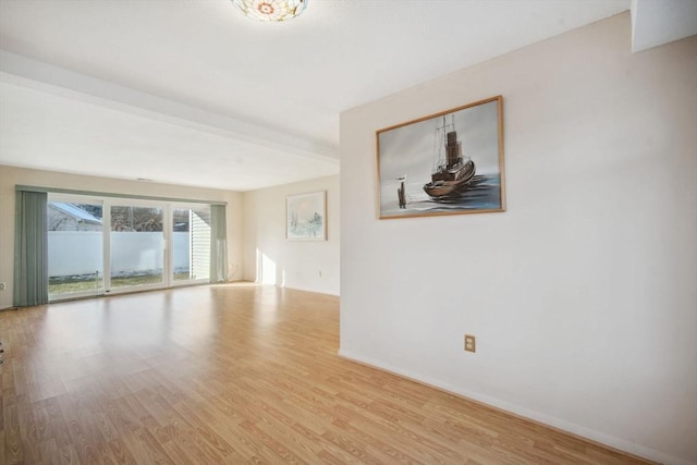 unfurnished room featuring beamed ceiling and light hardwood / wood-style floors