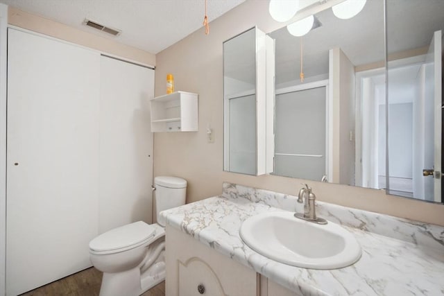 bathroom featuring vanity, toilet, a shower with door, and wood-type flooring