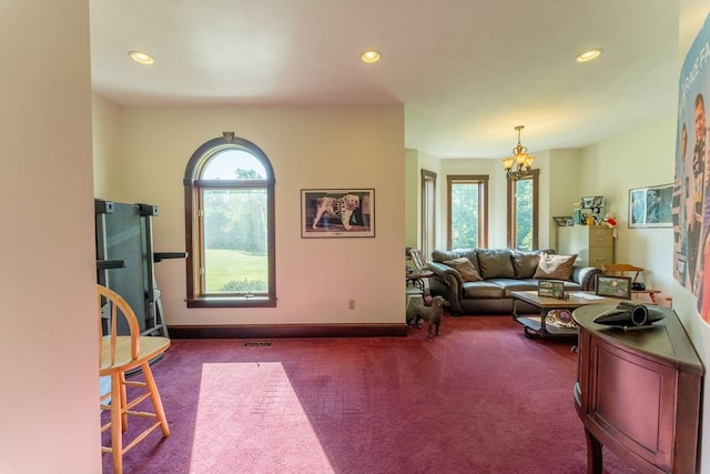 carpeted living room featuring a notable chandelier and plenty of natural light