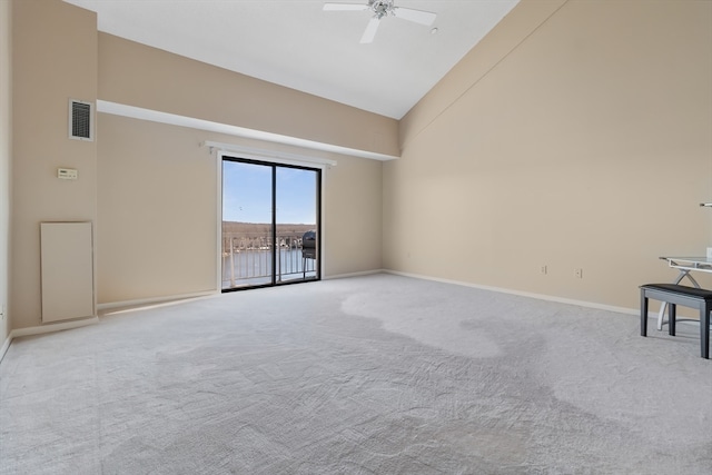 carpeted spare room with ceiling fan and high vaulted ceiling