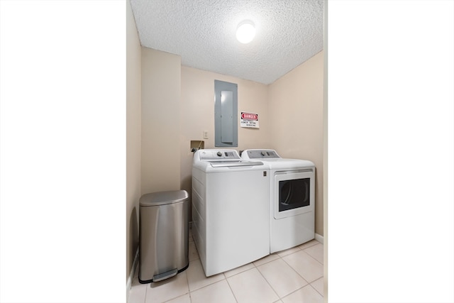 laundry room featuring washing machine and clothes dryer, light tile floors, and a textured ceiling