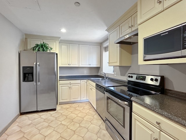 kitchen featuring stainless steel appliances, cream cabinets, sink, and light tile floors