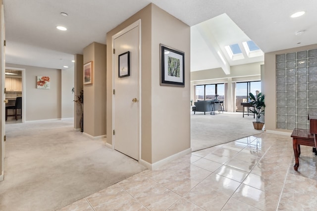 hallway featuring vaulted ceiling with skylight and light carpet