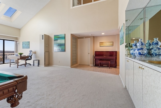 interior space featuring a skylight, light carpet, and high vaulted ceiling