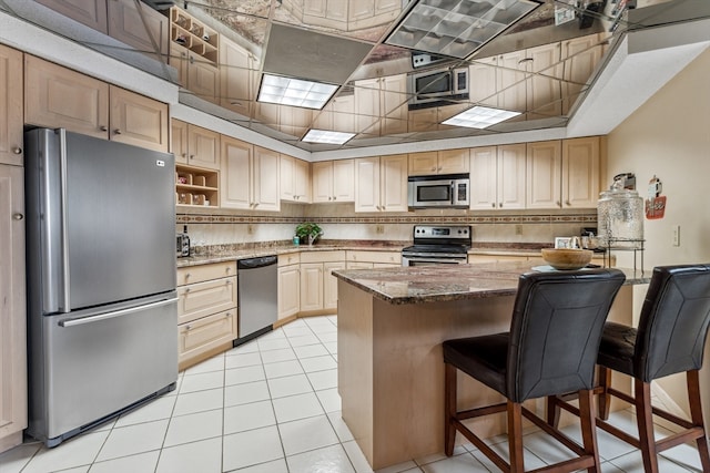 kitchen featuring a kitchen breakfast bar, dark stone counters, backsplash, and stainless steel appliances