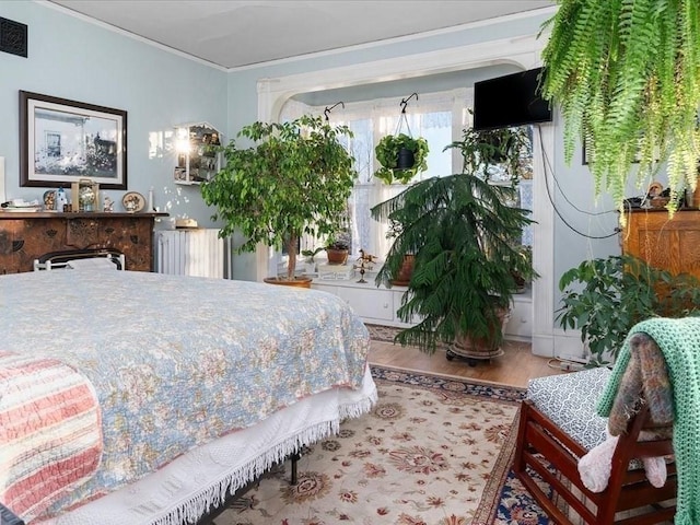 bedroom featuring radiator heating unit, ornamental molding, and hardwood / wood-style flooring