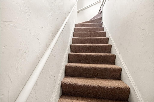 stairway featuring a textured wall