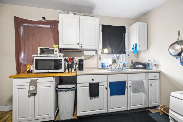 kitchen featuring white cabinetry, light countertops, a sink, and stainless steel microwave