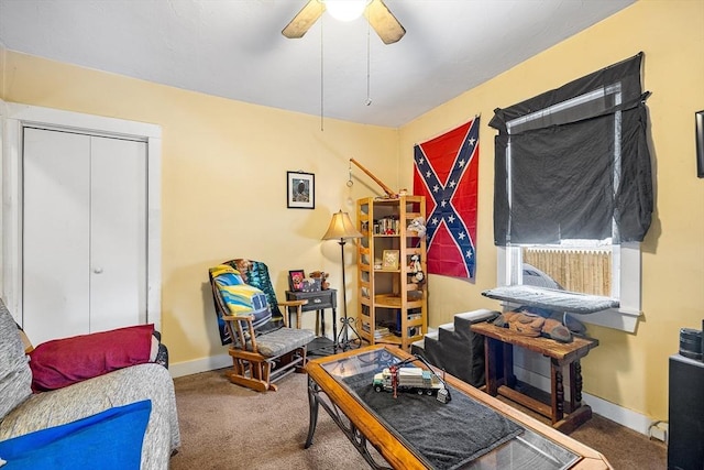 sitting room featuring carpet floors, baseboards, and a ceiling fan