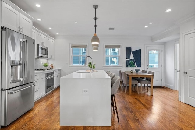 kitchen with stainless steel appliances, a kitchen island with sink, sink, and white cabinets