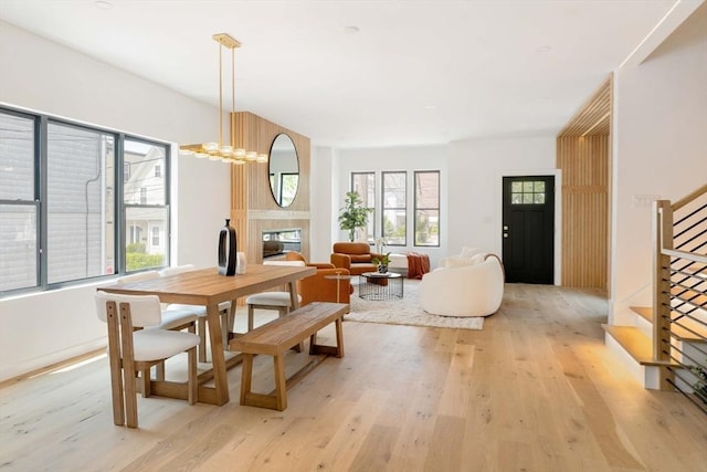 dining room featuring light wood-type flooring, an inviting chandelier, and a fireplace