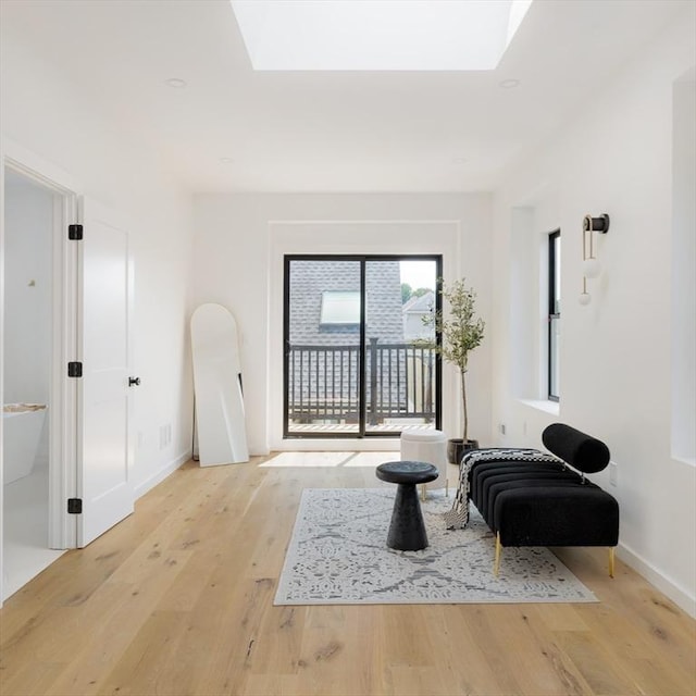 living area featuring light hardwood / wood-style floors and a skylight