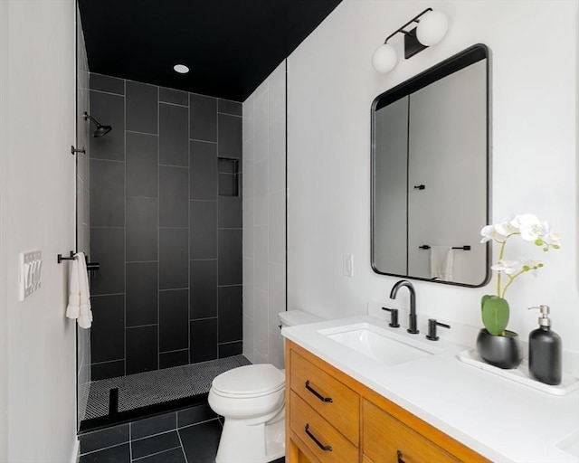 bathroom with tile patterned flooring, vanity, tiled shower, and toilet