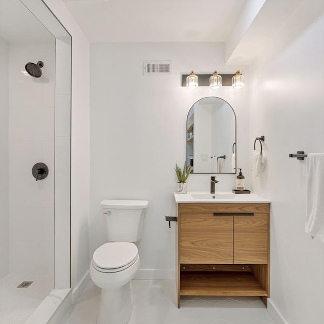 bathroom with tile patterned flooring, vanity, tiled shower, and toilet