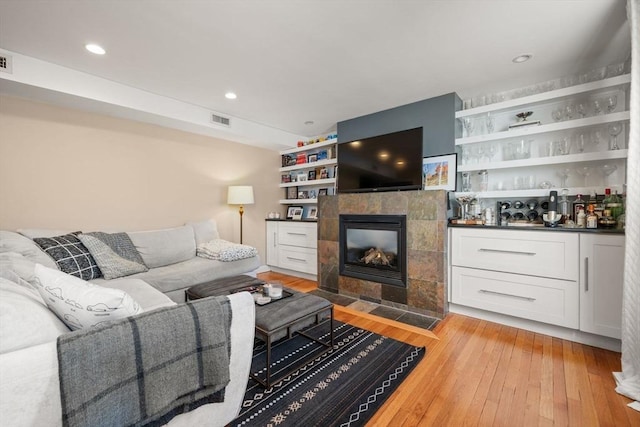 living room featuring a tiled fireplace and light wood-type flooring