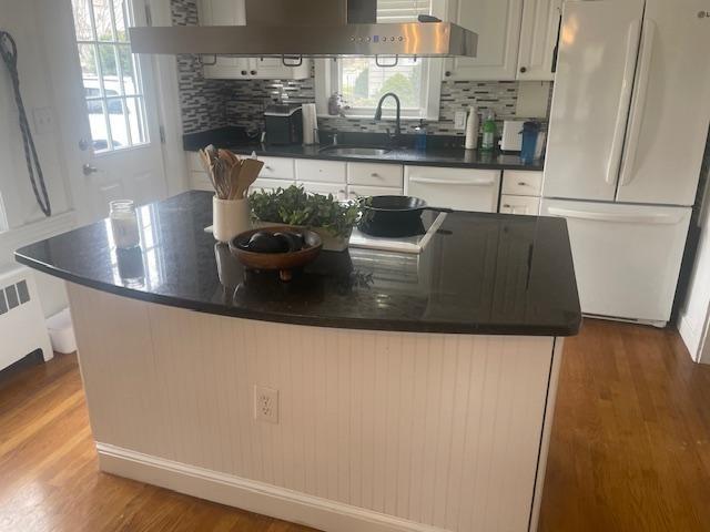 kitchen with white appliances, dark countertops, light wood-type flooring, and a sink