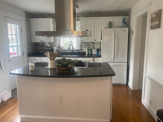kitchen with freestanding refrigerator, island exhaust hood, dark countertops, white cabinets, and dark wood-style flooring
