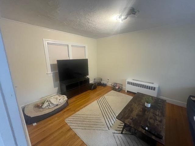 living room with a textured ceiling, baseboards, and wood finished floors