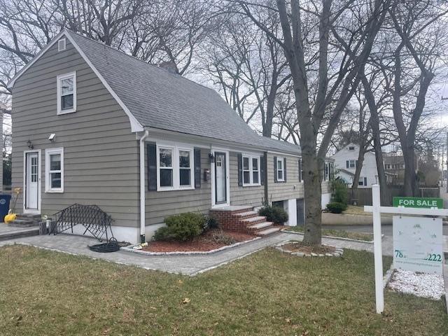 view of front of house featuring entry steps, a shingled roof, and a front lawn