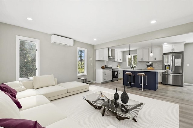 living room featuring recessed lighting, a baseboard heating unit, a wall mounted AC, and light wood-type flooring