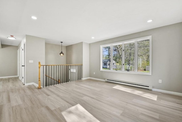 empty room featuring baseboards, baseboard heating, recessed lighting, and wood finished floors