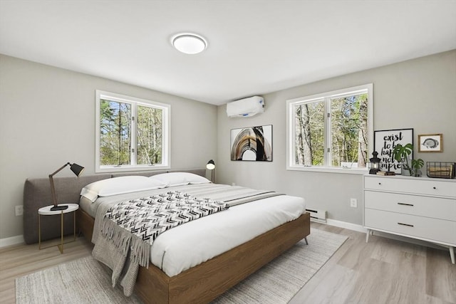 bedroom featuring an AC wall unit, a baseboard radiator, light wood-style floors, and multiple windows
