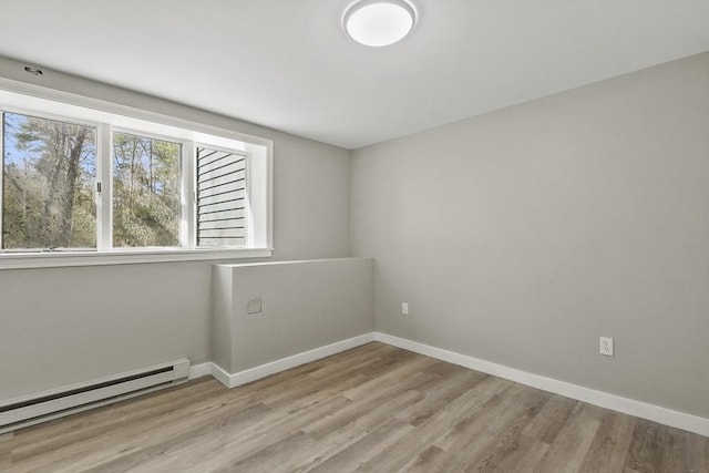 empty room featuring baseboards, wood finished floors, and a baseboard radiator