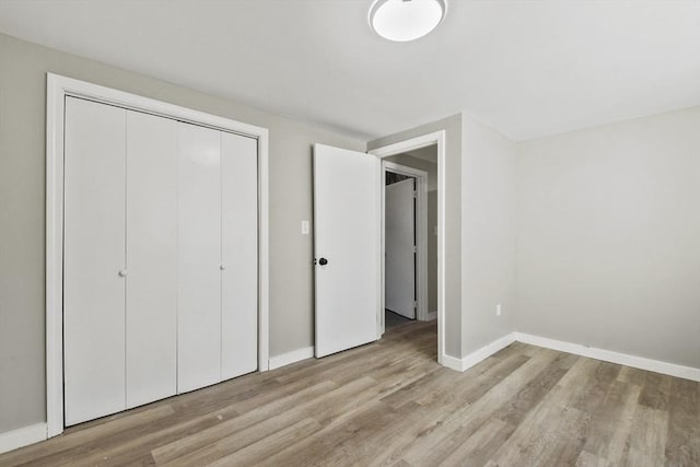 unfurnished bedroom with baseboards, wood finished floors, and a closet
