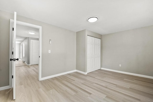 unfurnished bedroom with light wood-type flooring, baseboards, and a closet