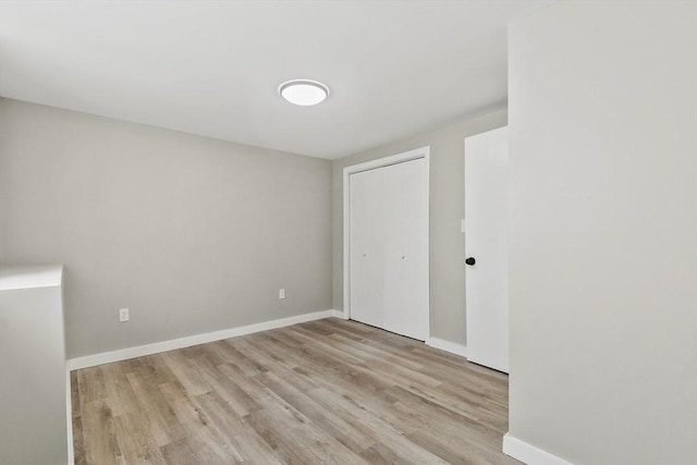 unfurnished bedroom with baseboards, wood finished floors, and a closet