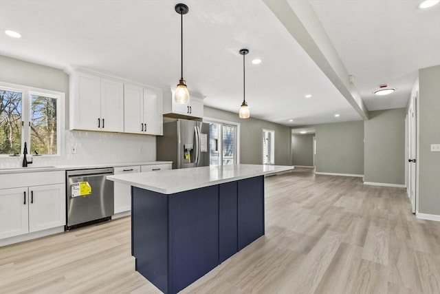 kitchen with light countertops, white cabinets, a sink, light wood finished floors, and appliances with stainless steel finishes