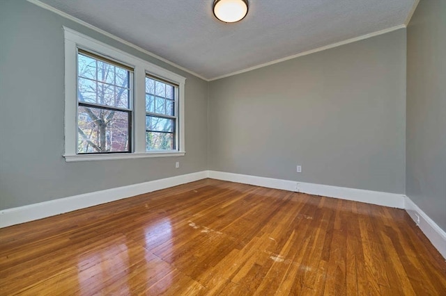 empty room featuring wood-type flooring, a textured ceiling, and ornamental molding