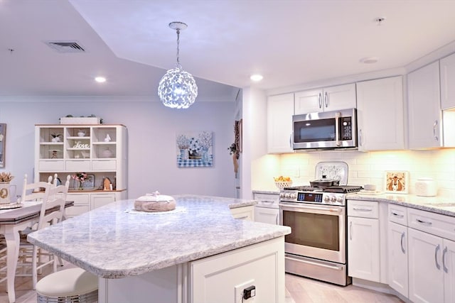 11 Cushing Pl Unit 106, Chelmsford, MA 01824 - kitchen with stainless steel appliances, a kitchen island, tasteful backsplash, white cabinets, and crown molding