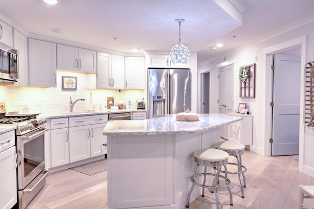 11 Cushing Pl Unit 106, Chelmsford, MA 01824 - kitchen featuring stainless steel appliances, a sink, white cabinetry, a breakfast bar, and a center island