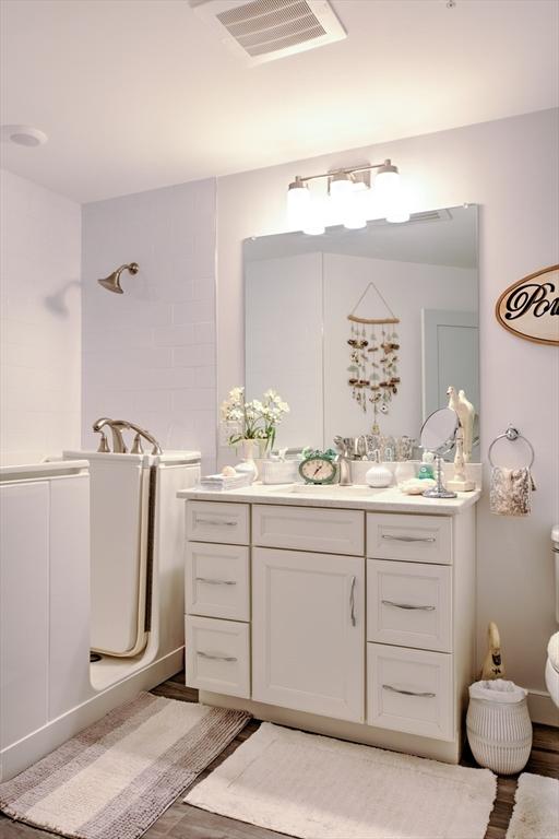 11 Cushing Pl Unit 106, Chelmsford, MA 01824 - full bathroom with a walk in shower, vanity, wood finished floors, and toilet