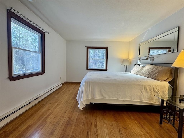 bedroom with hardwood / wood-style floors and a baseboard radiator