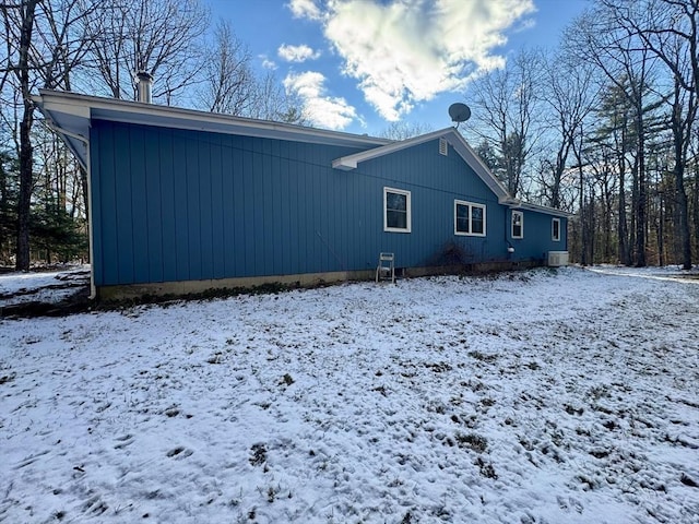 snow covered back of property featuring central AC unit