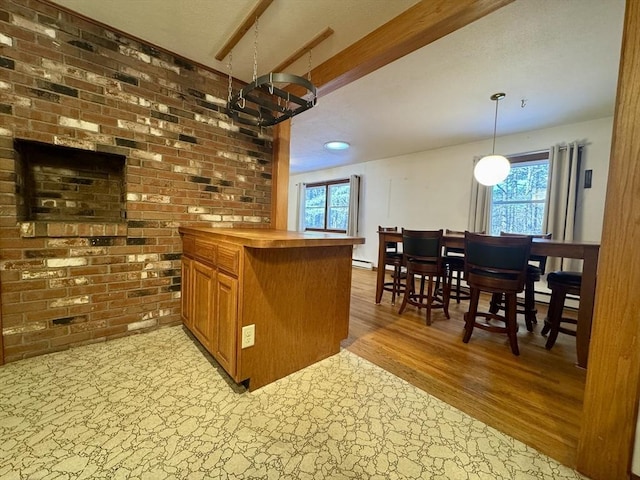 bar featuring a healthy amount of sunlight, light wood-type flooring, hanging light fixtures, and brick wall