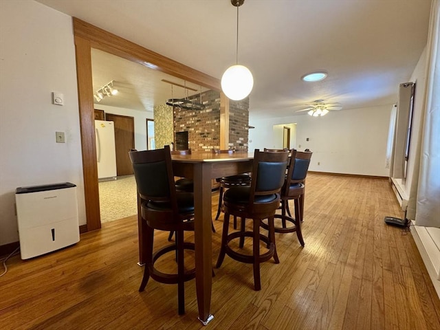 dining room featuring ceiling fan, hardwood / wood-style floors, and a baseboard heating unit