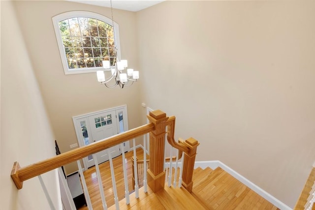 stairway with a chandelier, baseboards, and wood finished floors