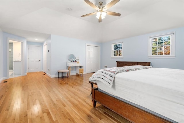 bedroom featuring a closet, visible vents, light wood-style floors, vaulted ceiling, and baseboards